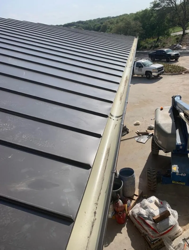 Standing seam panel and gutter detail on a metal roofing jobsite in Inkster